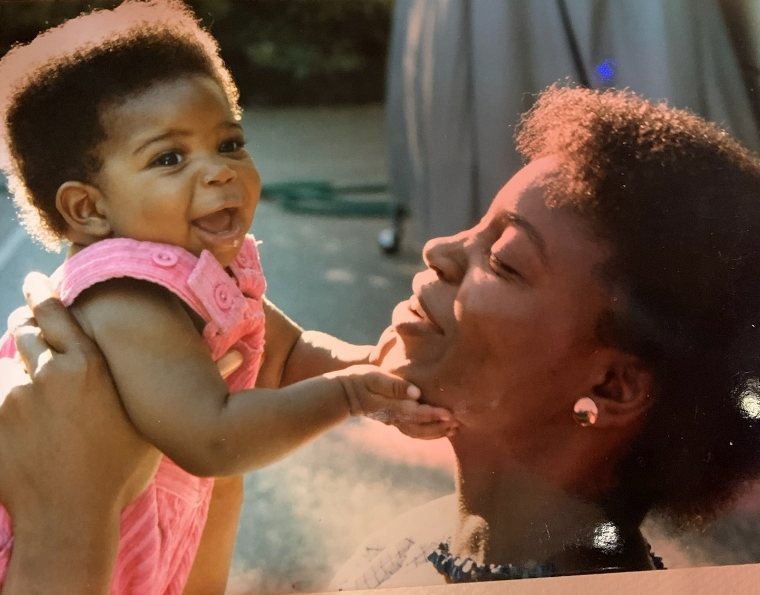 Baby Charisse Fontes laughing in a pink romper as her mom holds her up
